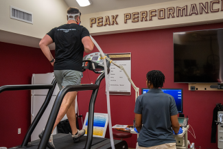 A man running on a treadmill with the words "Peak Performance" displayed behind him