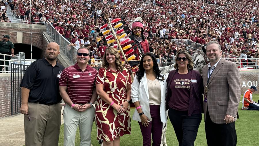 Six individuals standing on-field at a football game