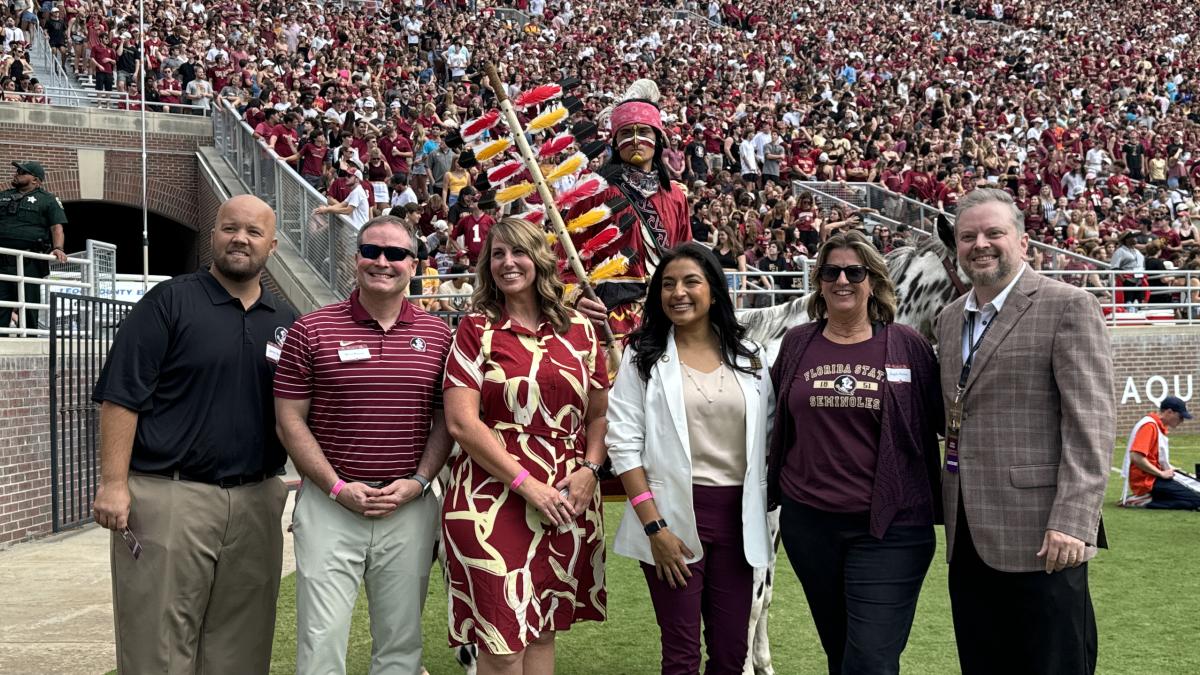 Six individuals standing on-field at a football game