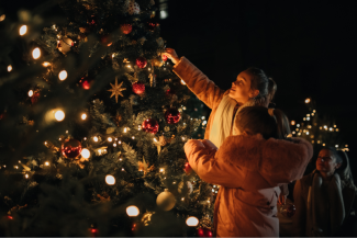 Children decorating a holiday tree outdoors