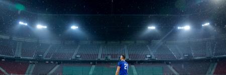 soccer player standing in middle of field in empty stadium