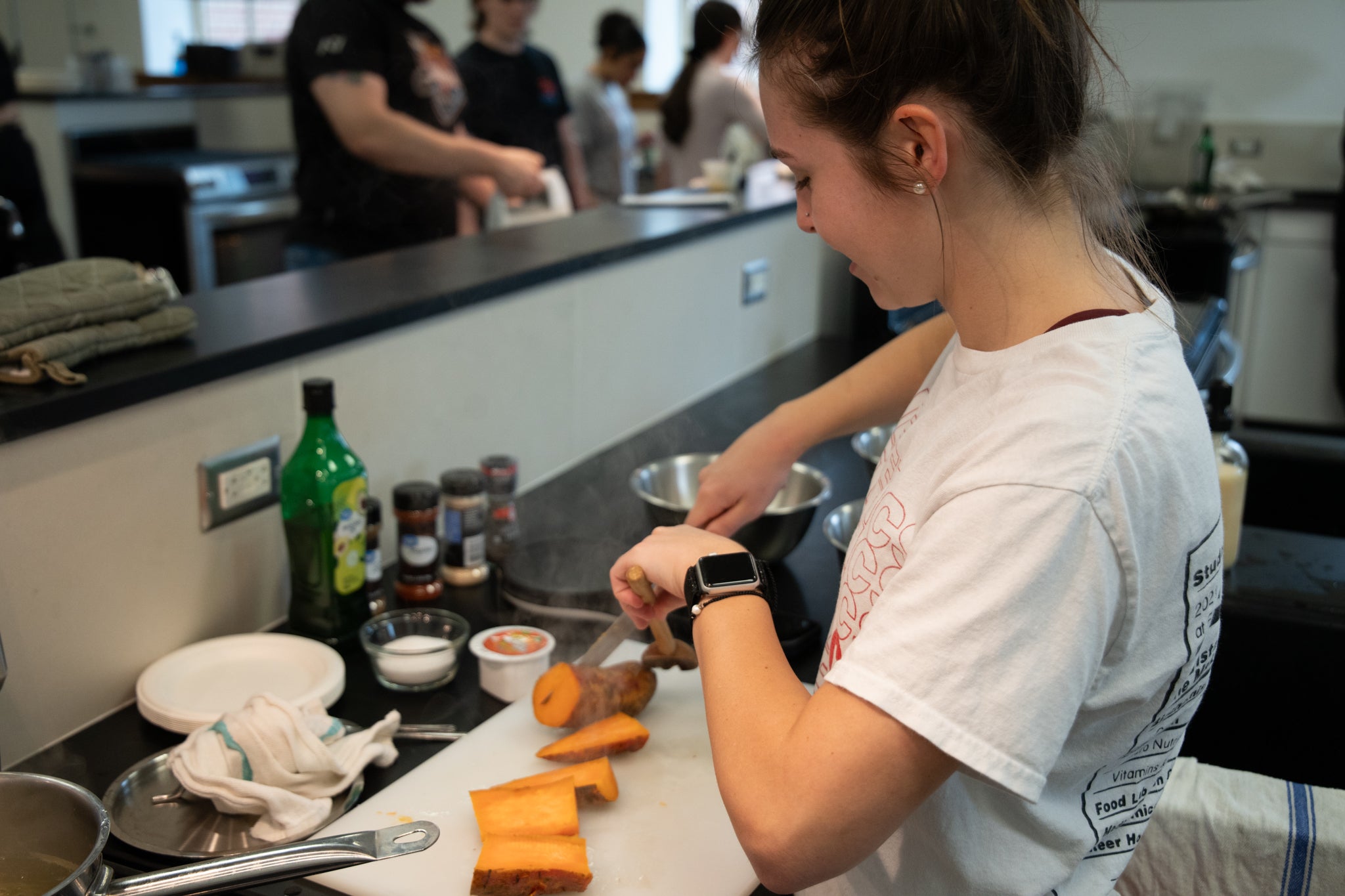 Student cutting potatoes on a countertop in a large kitchen